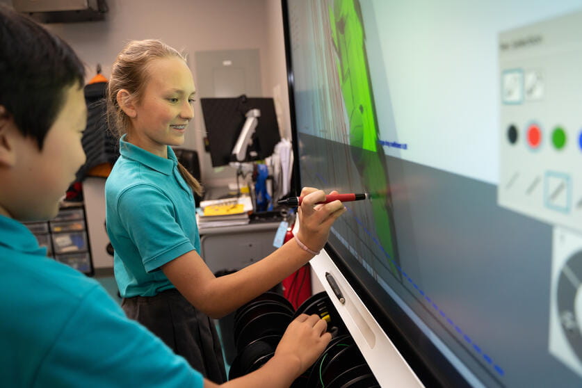 Students writing on an interactive white board