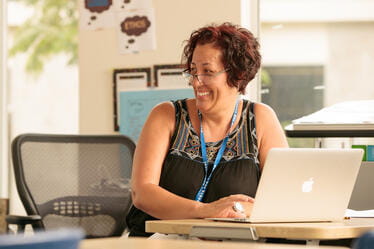 Smiling school staff member using a laptop